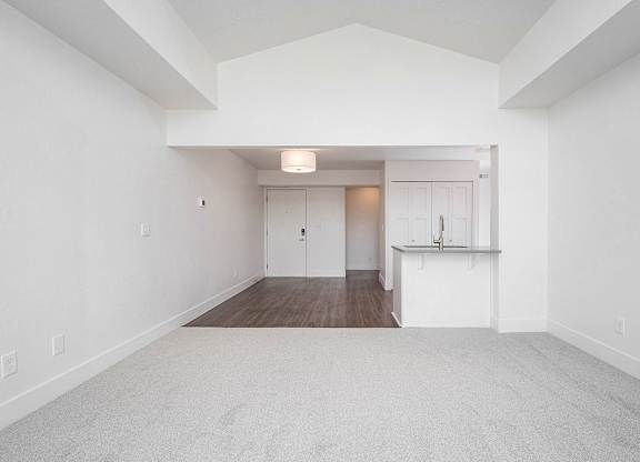 A large, empty living and dining room with a carpeted floor at The Crossings Apartments, Grand Rapids, MI, 49508