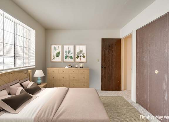 A bedroom with a bed, nightstand, and a painting on the wall at Beacon Hill and Great Oaks Apartments, Rockford, Illinois