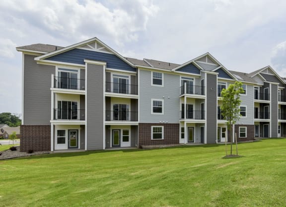an image of an apartment building with a green lawn at Dodson Pointe Apartment Homes, Rogers, AR, 72758