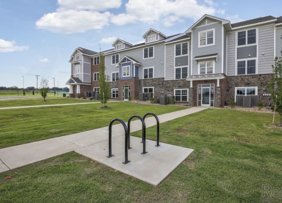 an apartment building with a bike rack on the sidewalk at Dodson Pointe Apartment Homes, Rogers