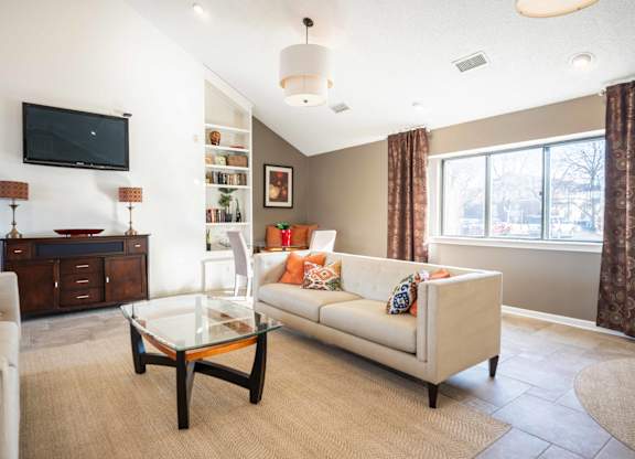 A living room with a white couch and a glass coffee table.