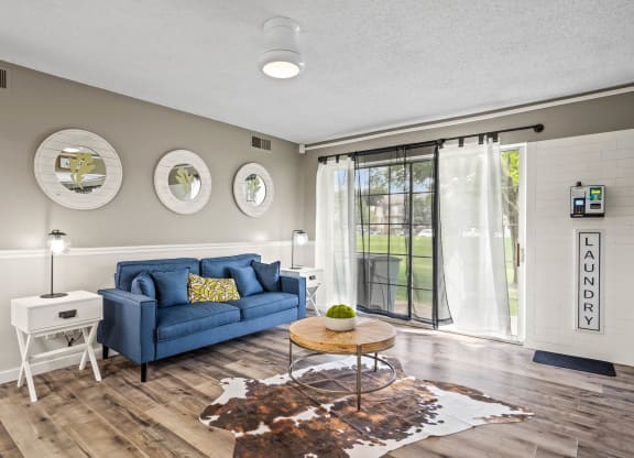 a living room with a blue couch and a coffee table at Beacon Hill and Great Oaks Apartments, Rockford, IL