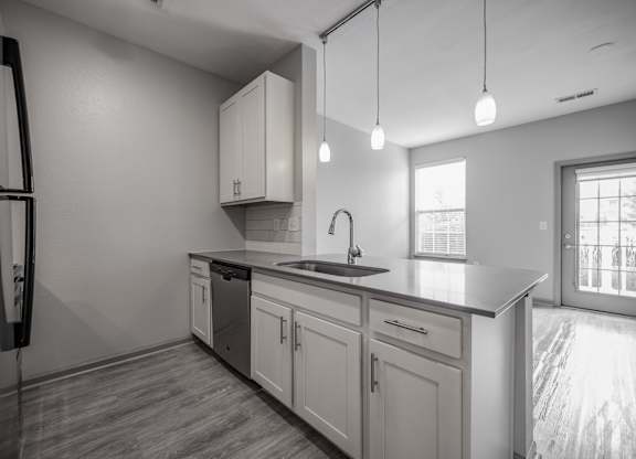 an empty kitchen with white cabinets and a black counter top at Bella Vista Apartments, Fishers, IN