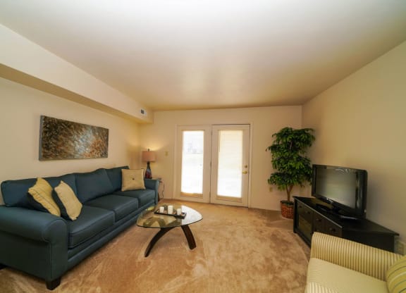Large living room with access to a private patio at Dupont Lakes Apartments, Fort Wayne, IN