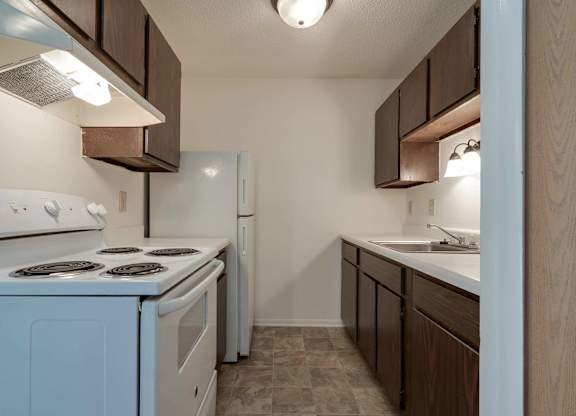 A kitchen with white appliances and wooden cabinets.