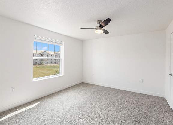 Bedroom with large window and ceiling fan at Eagle Ridge Apartment Homes, Traverse City, MI