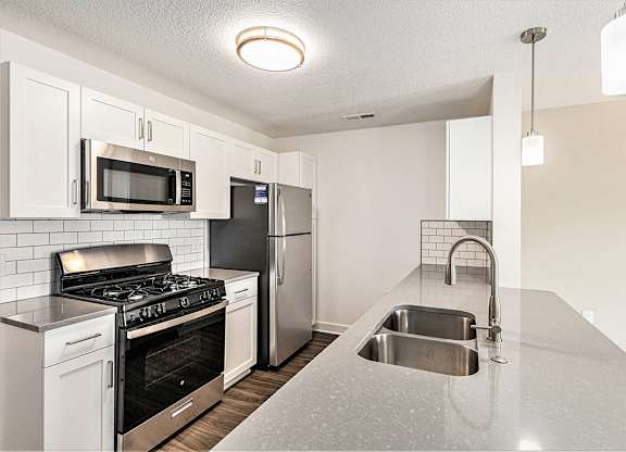 A two bedroom kitchen with a stove, microwave, refrigerator, and sink at Eagle Ridge Apartment Homes, Traverse City, Michigan