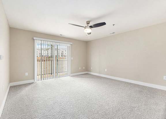A carpeted living room with a ceiling fan and a sliding glass door Spacious bedroom with large windows and walk in closet at Eagle Ridge Apartment Homes,  Michigan 49685