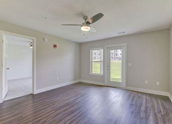 A living room with a ceiling fan and hard surface flooring Spacious bedroom with large windows and walk in closet at Eagle Ridge Apartment Homes,  Michigan 49685