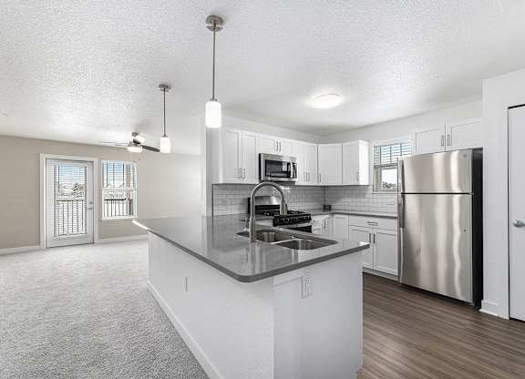 A living room and kitchen with a stainless steel refrigerator and a sink at Eagle Ridge Apartment Homes, Traverse City, Michigan