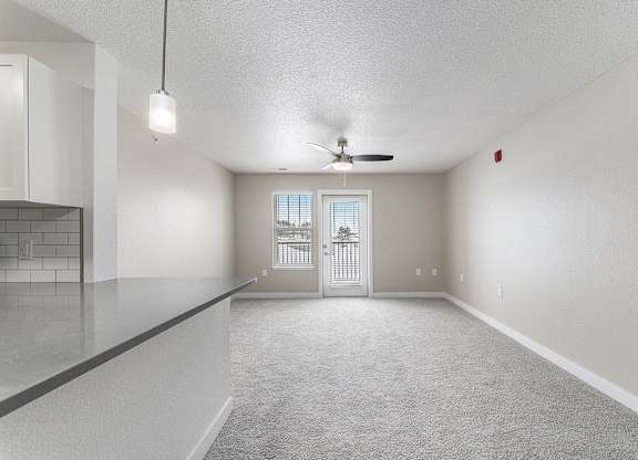 A spacious living room with a ceiling fan and a door leading to a patio at Eagle Ridge Apartment Homes, Traverse City, Michigan