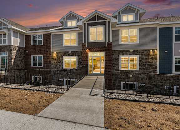 A modern apartment building with a sidewalk at Eagle Ridge Apartment Homes,  Michigan 49685