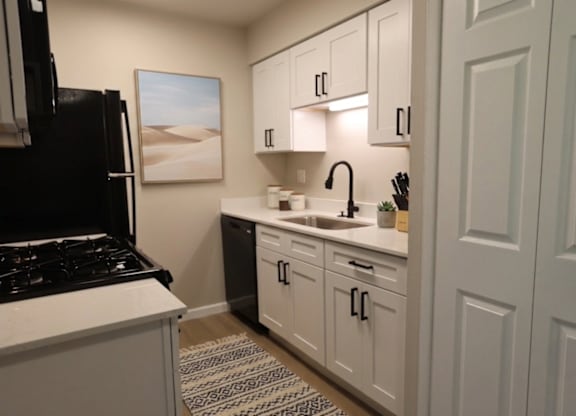 A kitchen with white cabinets and a black stove top oven.