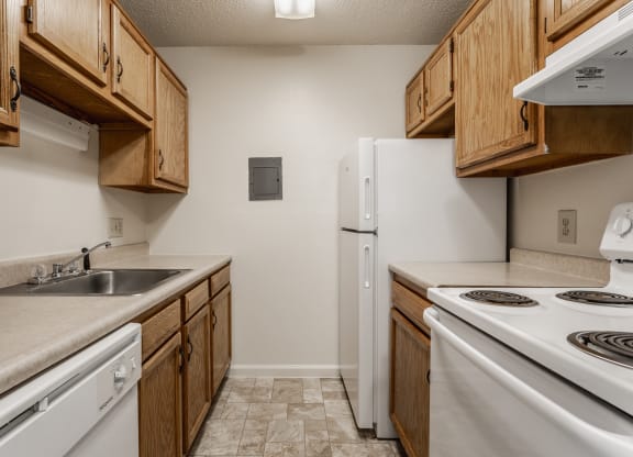 a kitchen with wooden cabinets and white appliances at Bavarian Village Apartments, Indianapolis