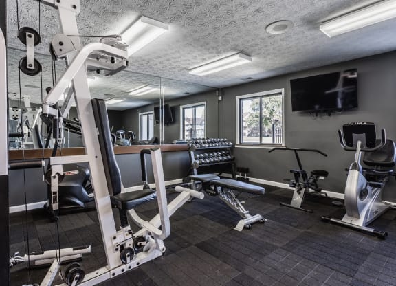 a gym with exercise equipment and a flat screen tv at Bavarian Village Apartments, Indianapolis