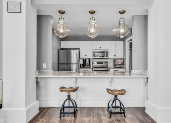 a kitchen with white cabinets and a bar with two stools at Trophy Club at Bellgrade, Midlothian, VA, 23113