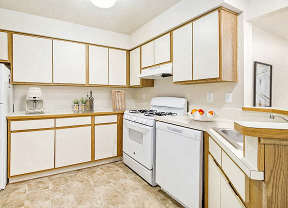 A kitchen with white appliances and wooden cabinets at Emerald Park Apartments, Kalamazoo, Michigan