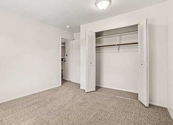 A white closet with a carpeted floor in a bedroom at Emerald Park Apartments, Kalamazoo, Michigan