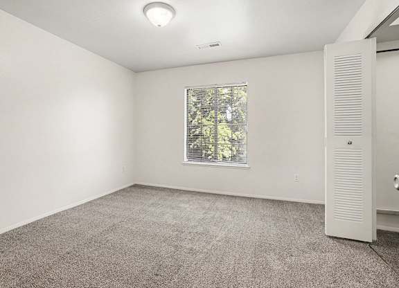 A bedroom with a window and a walk-in closet at Emerald Park Apartments, Kalamazoo, Michigan