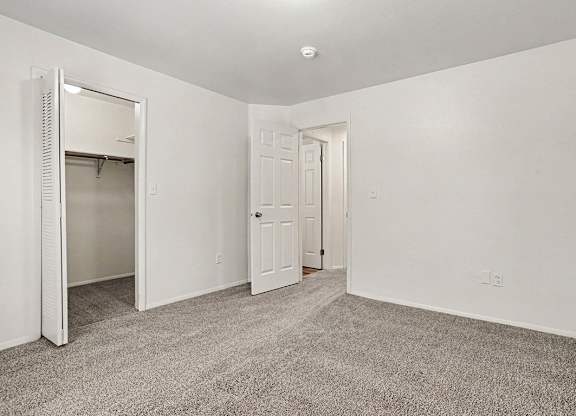 A spacious bedroom with a carpeted floor and a closet at Emerald Park Apartments, Kalamazoo, Michigan