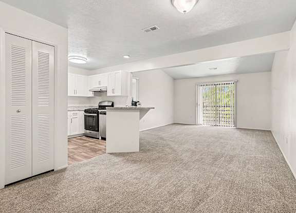 A kitchen with white cabinets and sliding glass doors to a balcony at Emerald Park Apartments, Kalamazoo, Michigan