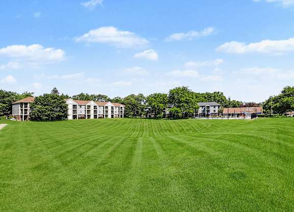 A large grassy field with a building in the background at Emerald Park Apartments in Kalamazoo, MI