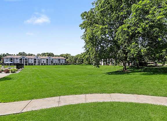 A grassy area with a building in the background at Emerald Park Apartments in Kalamazoo, MI
