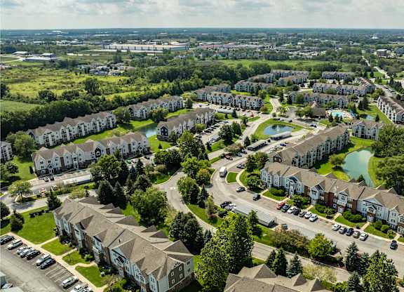 A bird's eye view of a residential area with houses, roads, and a swimming pool