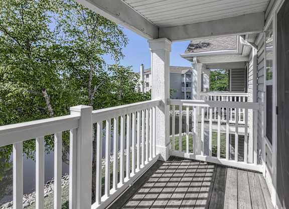 a porch with a white railing and a house in the background at Latitudes Apartments, Indianapolis