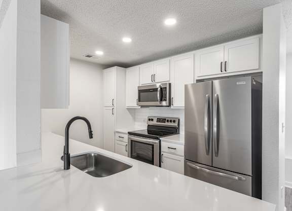 a kitchen with white cabinets and stainless steel appliances at Latitudes Apartments, Indiana, 46237