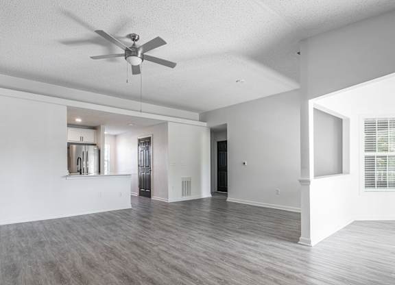 an empty living room and kitchen with a ceiling fan at Latitudes Apartments, Indiana