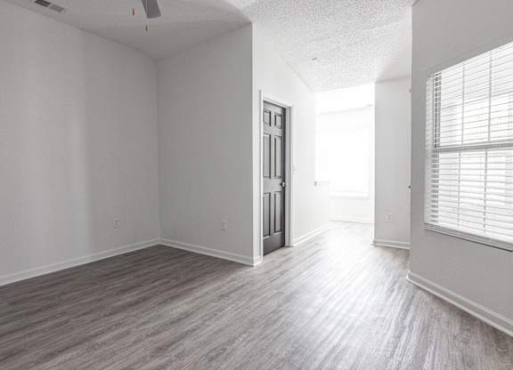an empty living room with white walls and wood floors at Latitudes Apartments, Indianapolis, IN