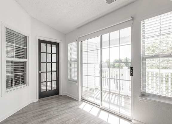 an empty living room with large windows and a door to a balcony at Latitudes Apartments, Indianapolis
