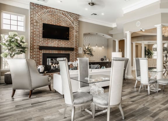 a dining room with a table and chairs and a brick fireplace at The Avenue at Polaris Apartments, Columbus, OH