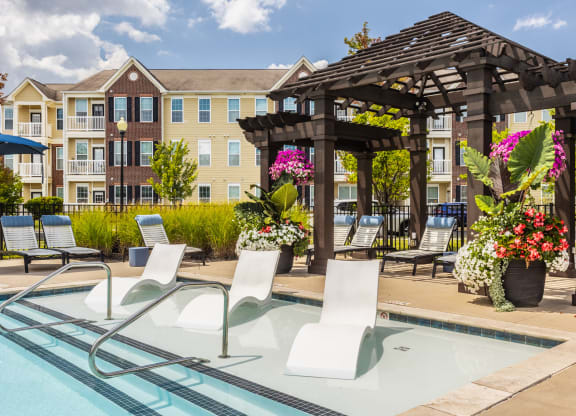 a swimming pool with lounge chairs and a gazebo with an apartment building at The Avenue at Polaris Apartments, Columbus, OH