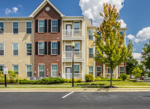an apartment building on the corner of a street with trees at The Avenue at Polaris Apartments, Columbus, OH