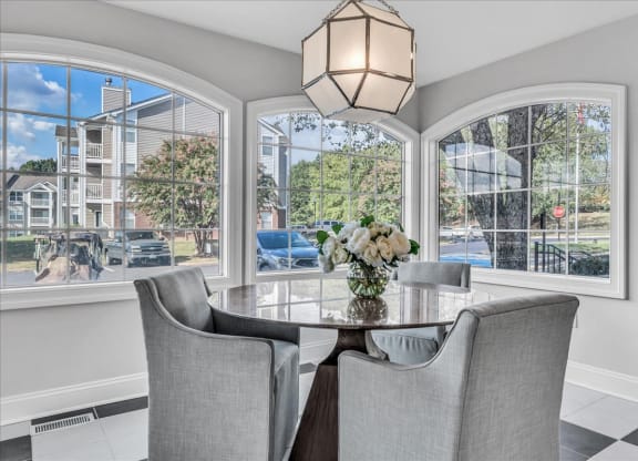 a dining room with large windows and a table with chairs at The Vinings Apartments in Richmond, VA