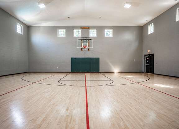 A basketball court with a green wall and a basketball hoop.