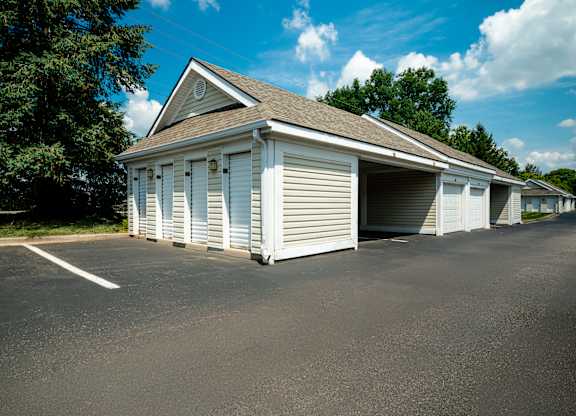 A white building with a grey roof and a parking lot in front.