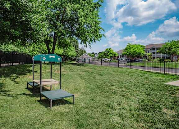 A green sign with a white arrow pointing to the right is on a pole in a grassy area.
