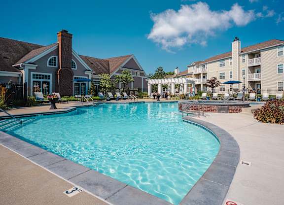 A large swimming pool in front of a building with a clear blue sky above.