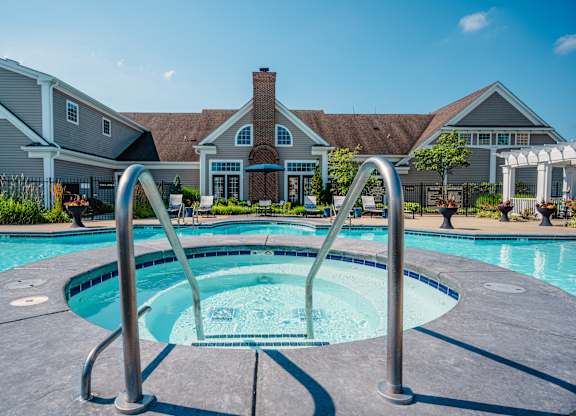 A swimming pool with a diving board in front of a house.