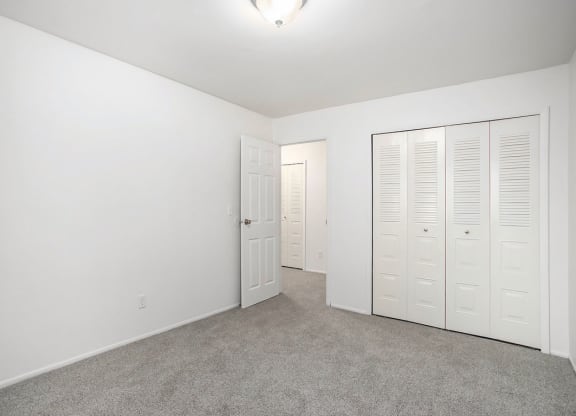an empty bedroom with white closets and carpeting at Fairlane Apartments in Springfield, MI