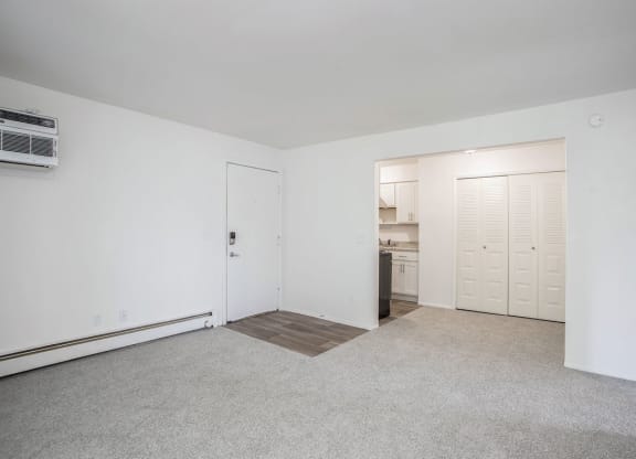 an empty living room with a kitchen in the background at Fairlane Apartments in Springfield, MI