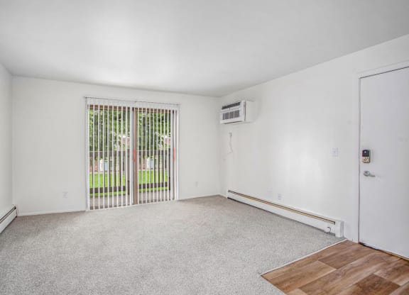 an empty living room with a slider to a private balcony at Fairlane Apartments in Springfield, MI