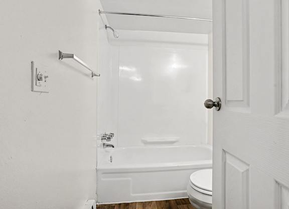White bathroom with tub shower combo and chrome fixtures at Fairlane Apartments, Michigan, 49037