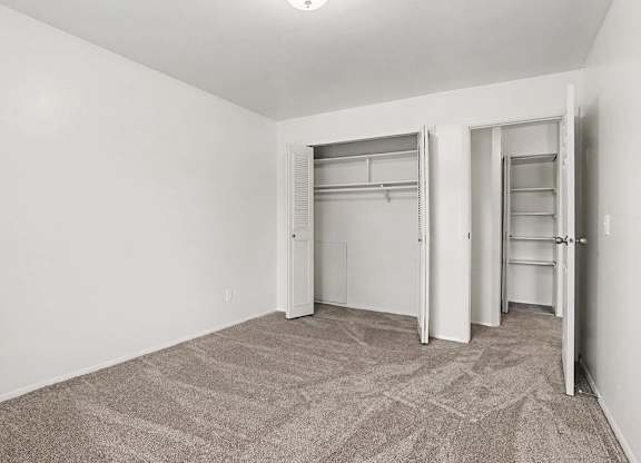 Empty bedroom with two closets and carpet flooring at Fairlane Apartments, Springfield, MI