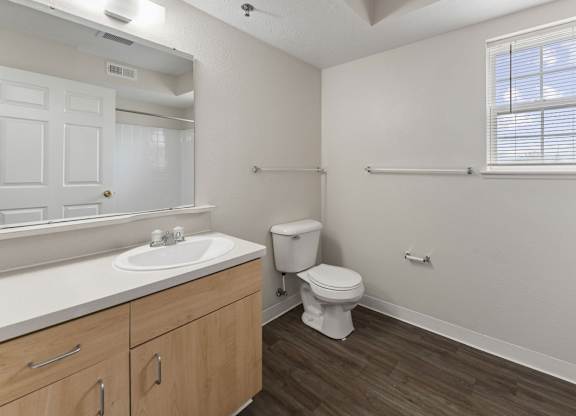 A bathroom with a window, toilet, sink, and mirror at Fieldstream Apartment Homes in IA 50023
