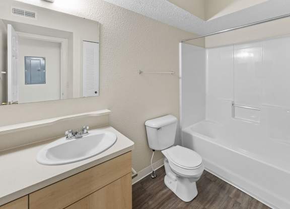 A white bathroom with a toilet, sink, and bathtub at Fieldstream Apartment Homes in IA 50023