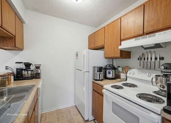 A kitchen with a white stove top oven and a white refrigerator.